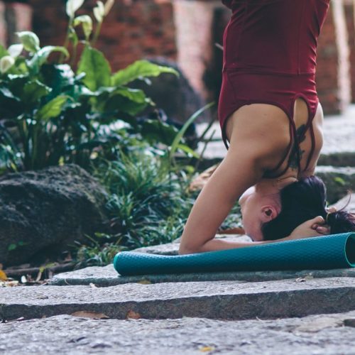woman doing headstand on yoga mat